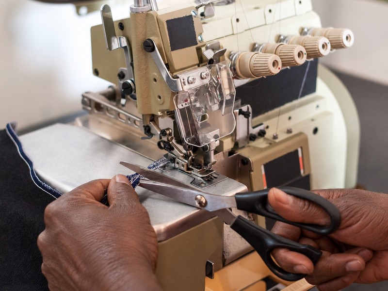 Hands trimming a fabric edge at an overlock sewing machine